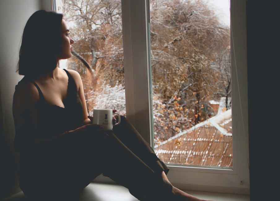 A sad Colombian woman sitting by the window.