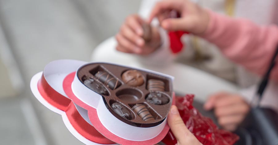 woman holding heart-shaped box of chocolates