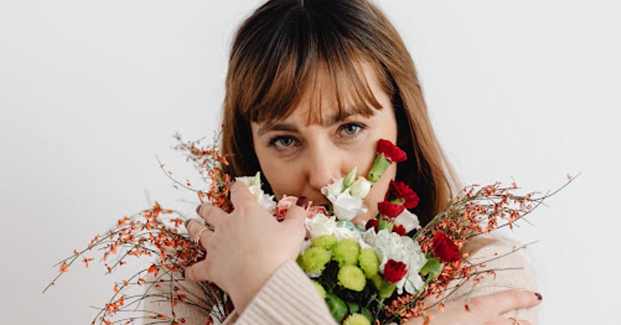 A photo of a Colombian woman embracing a set of flowers.